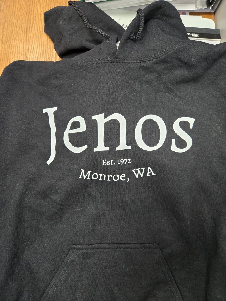 Black hoodie with "Jenos Est. 1972 Monroe, WA" printed in white text on the front.