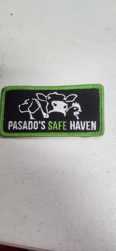 Rectangular patch with green border, showing outlines of a cow, pig, and chicken, and text "Pasado's Safe Haven.