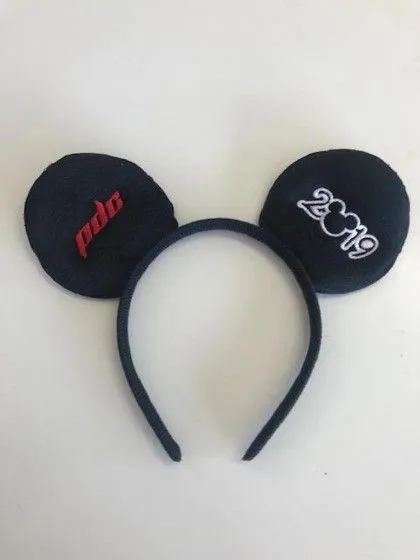 Black headband with two round mouse ears, one labeled "pdc" and the other labeled "2019," on a white surface.