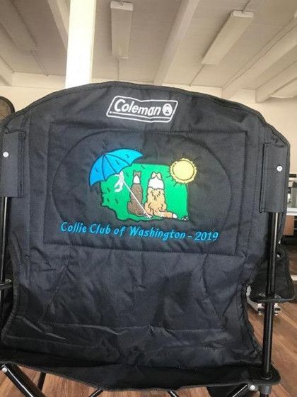 Black Coleman chair with embroidered "Collie Club of Washington - 2019" logo featuring two collies, sun, and umbrella.