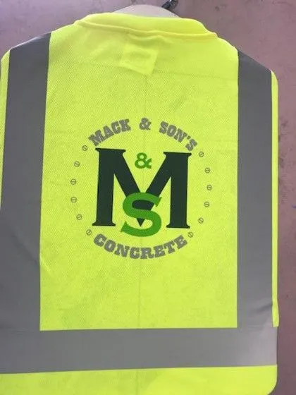 A yellow safety vest with “Mack & Son’s Concrete” and large “M&S” logo printed on the back.