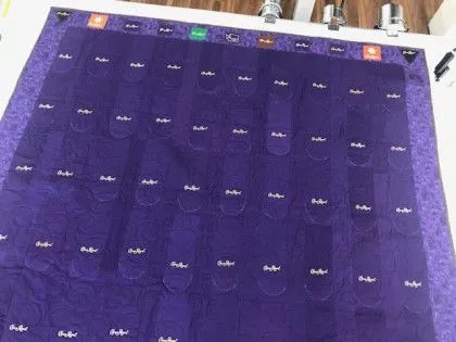 A purple Jeopardy game board with labeled pockets and rows on a table, ready for gameplay.
