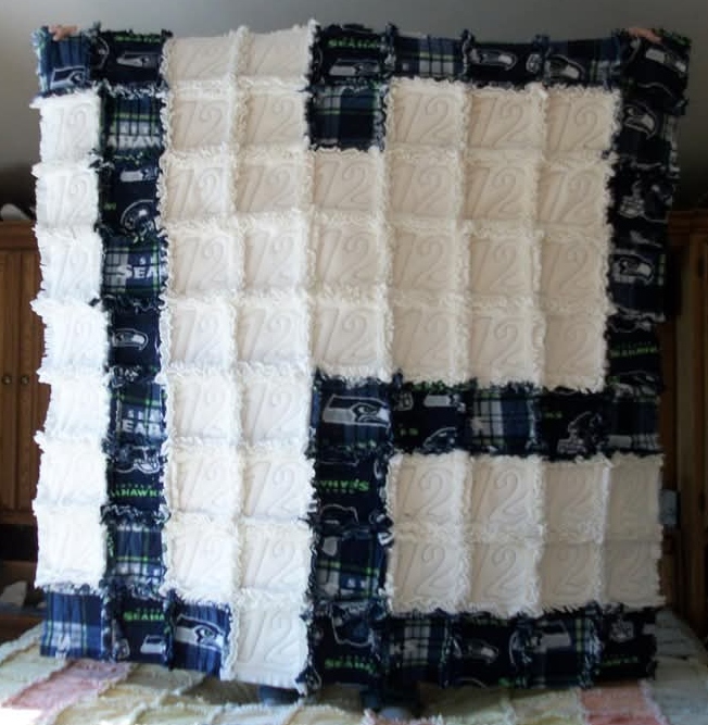 A patchwork quilt with cream and Seahawks-themed blue, green, and plaid squares displayed indoors.