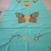 Teal fabric with gold illustrations of a butterfly, hot air balloon, birds, and the words "Journey," "Explore," "Inspire.