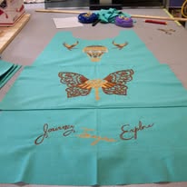 A teal fabric with gold designs of antlers, a dreamcatcher, a butterfly, and the words "Journey" and "Explore.