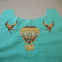 Turquoise fabric with an embroidered hot air balloon and two birds flying on either side.